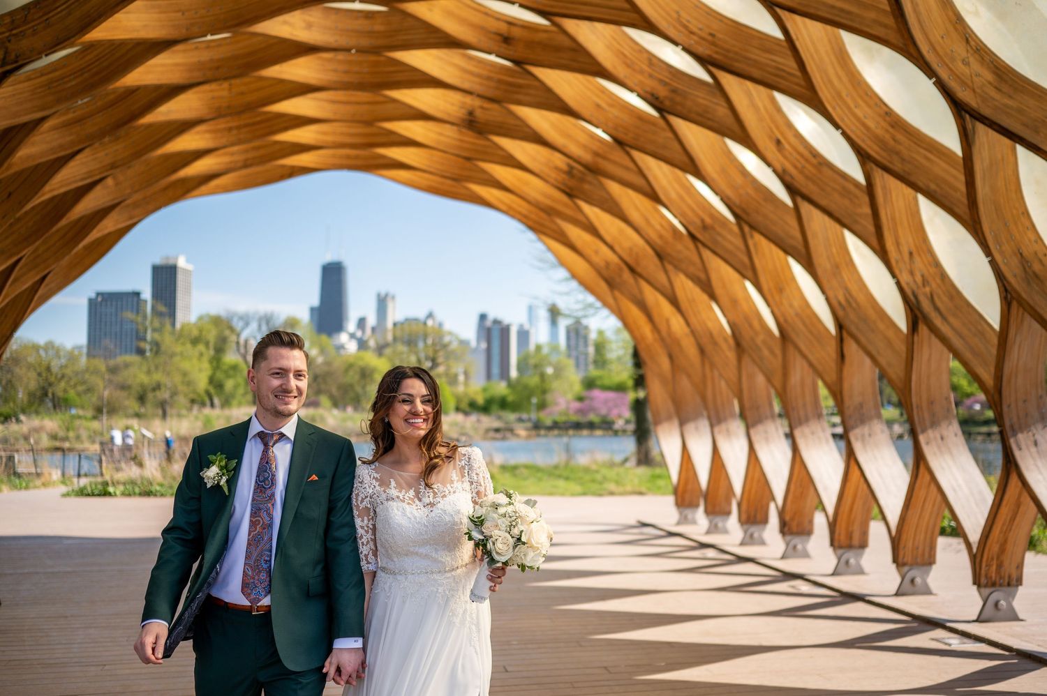 A couple poses for wedding photos in Lincoln Park's honeycomb-shaped wooden pavilion with Chicago skyline views.