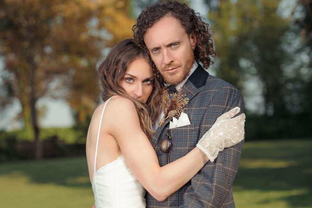 A romantic couple shares tender moments in an outdoor autumn setting during their wedding photoshoot.
