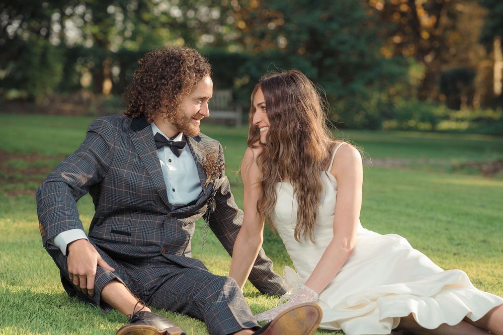 Bride and groom share playful moments in a grassy outdoor setting during their wedding photoshoot.