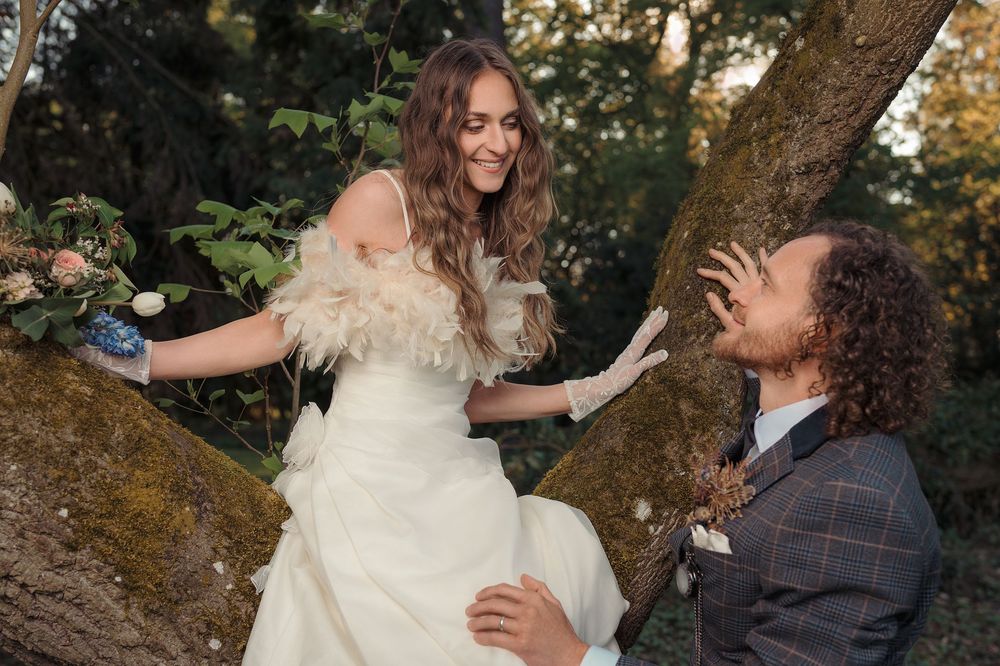 A romantic couple shares a tender moment dancing together outdoors under tall trees at sunset.