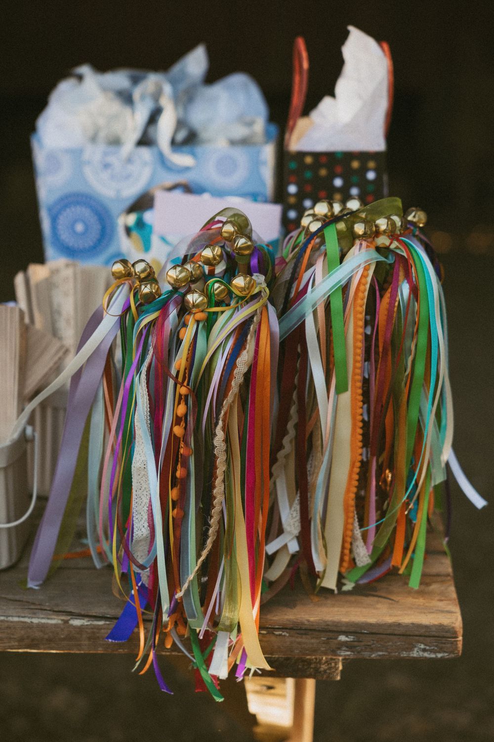 Colorful ribbons and bells decoratively hanging from a wooden surface create a festive wedding or celebration display.