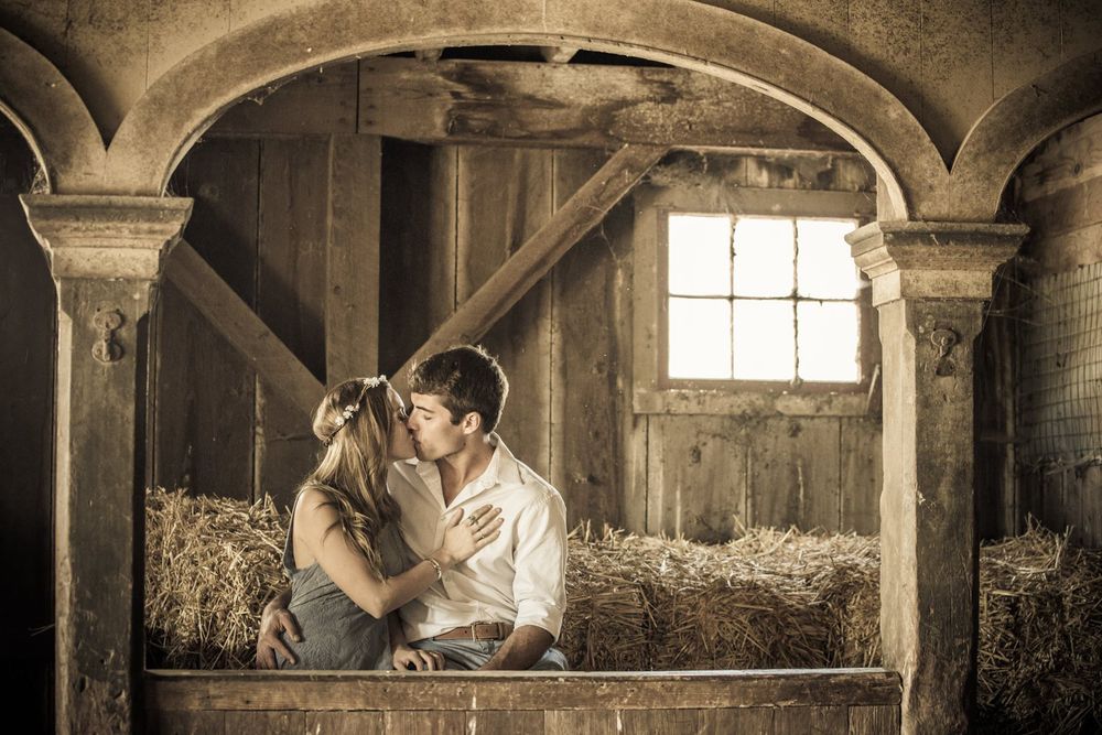 Rustic barn interior with wooden beams and sunlight streaming through windows.
