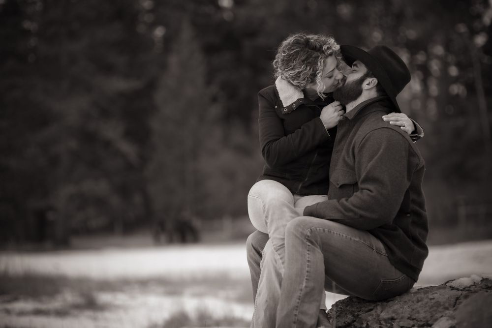 Couple sharing intimate moment on outdoor bench in black and white photography.