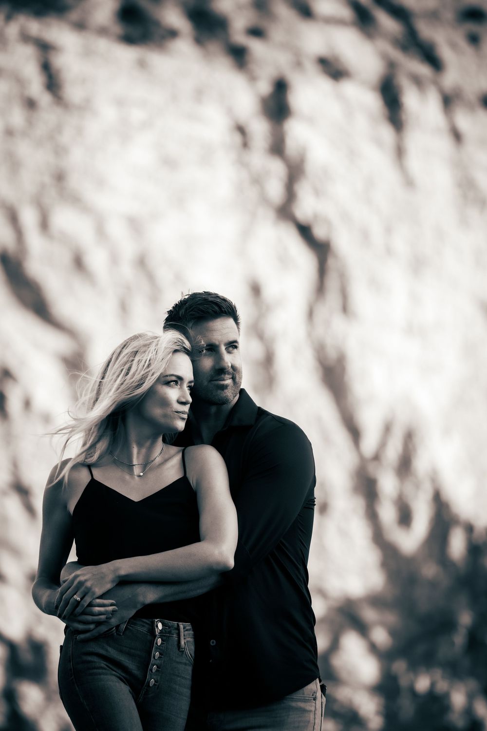 Romantic couple photoshoot in black and white showing tender moments against a textured background.