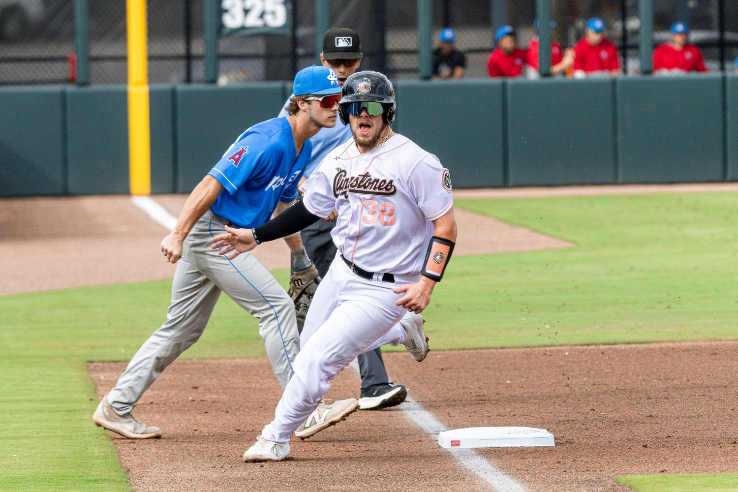 Baseball player slides into base during professional game while opponent awaits throw from infield.