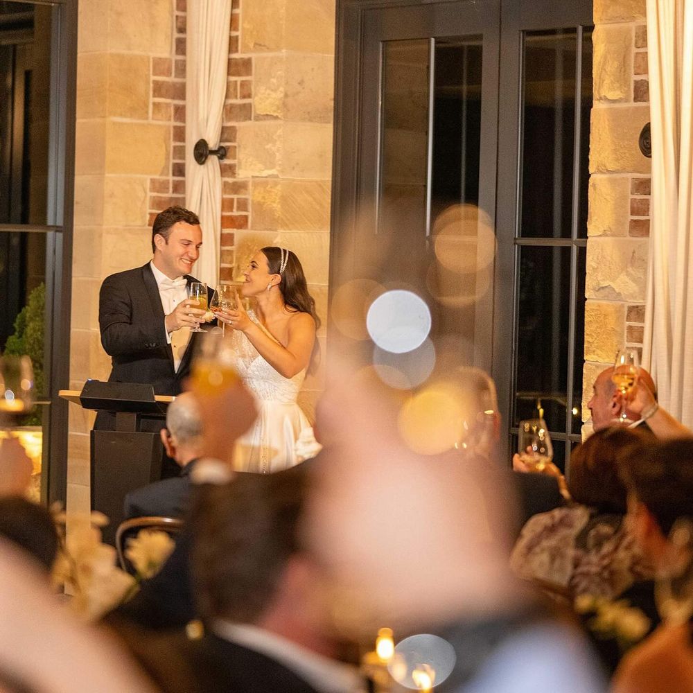 Bride and groom share a champagne toast at their elegant evening wedding reception with guests.