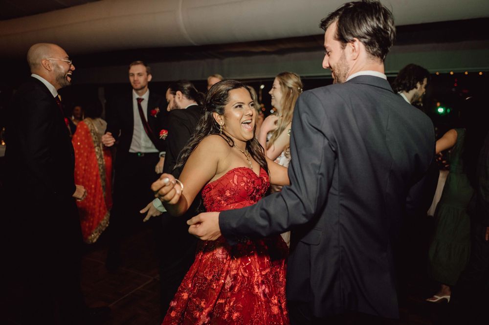 Guests in formal attire dancing joyfully at a lively wedding reception on the dance floor.