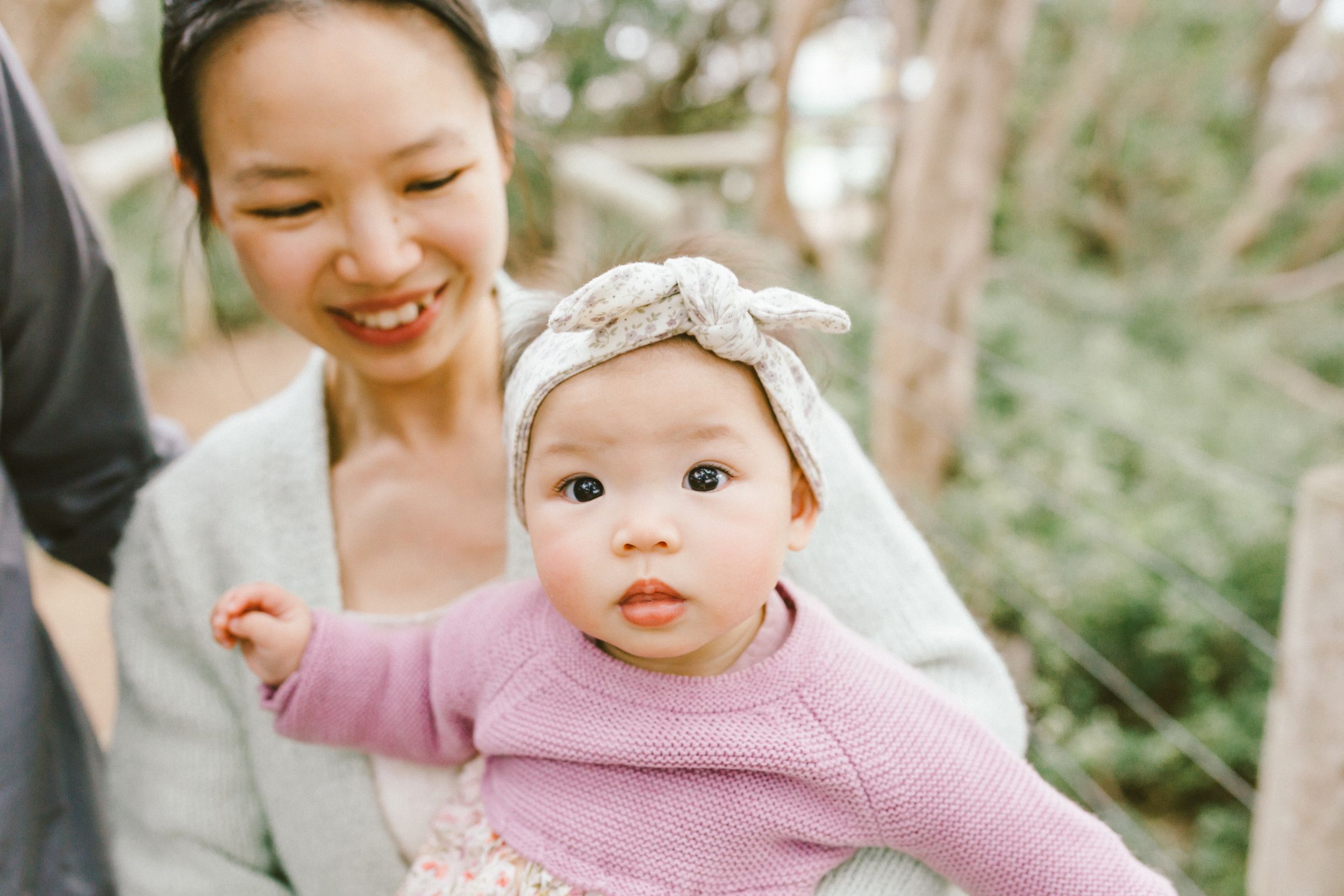 A family sits together on lush grass during a sunny outdoor photo session.