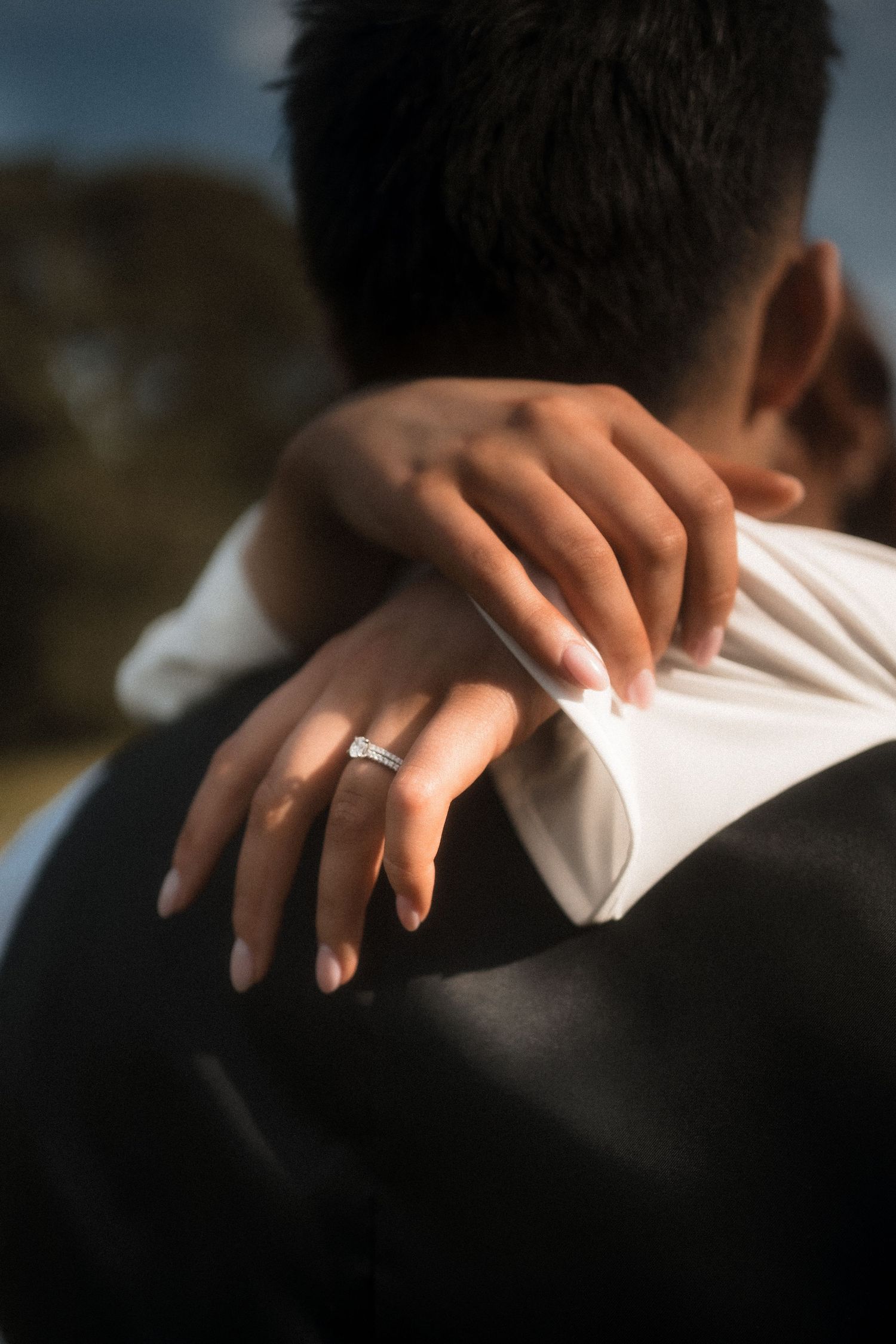 Close-up shot of hands resting on a white dress in dramatic lighting.