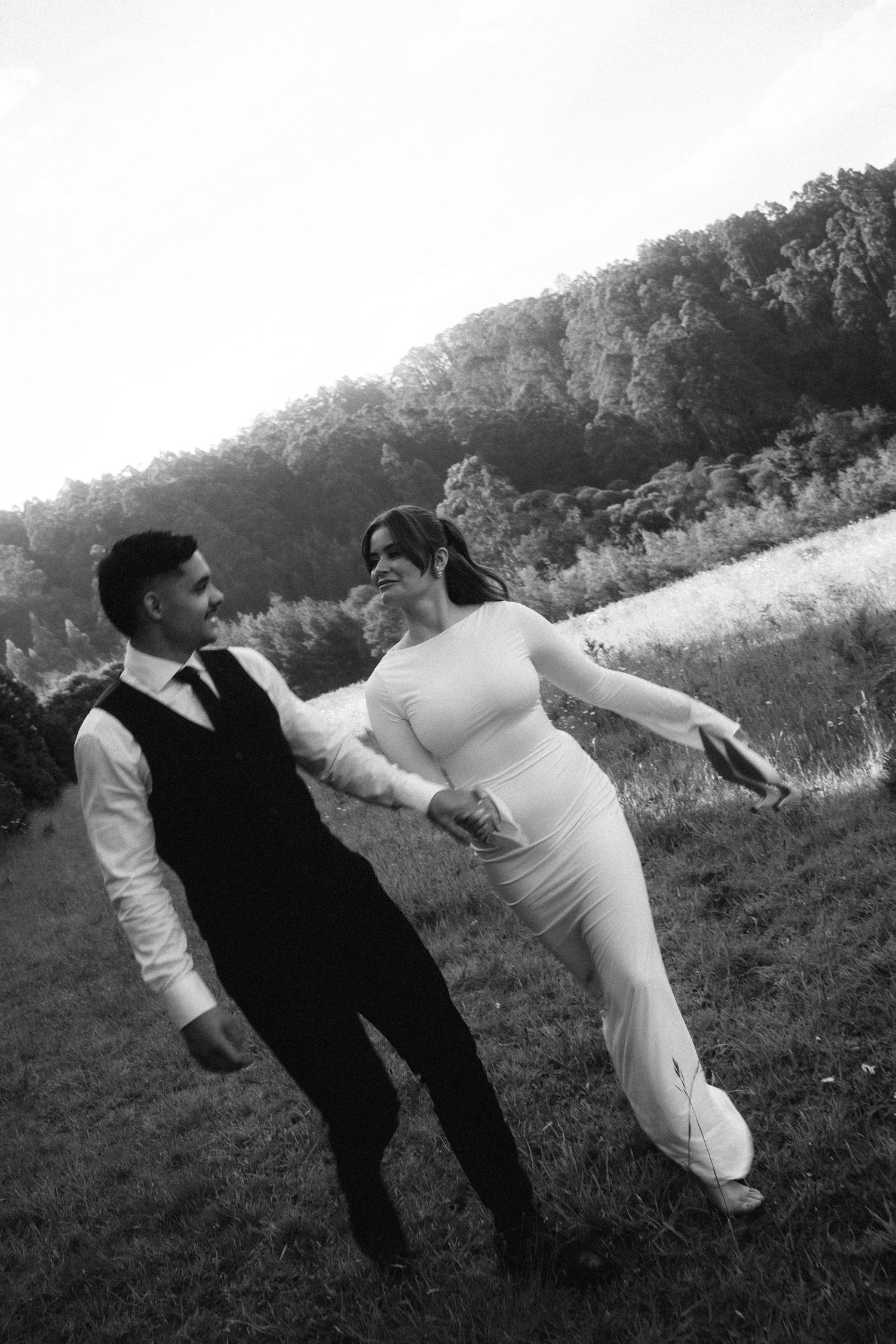 Two figures in black and white perform a synchronized falling motion sequence across a grassy outdoor setting.
