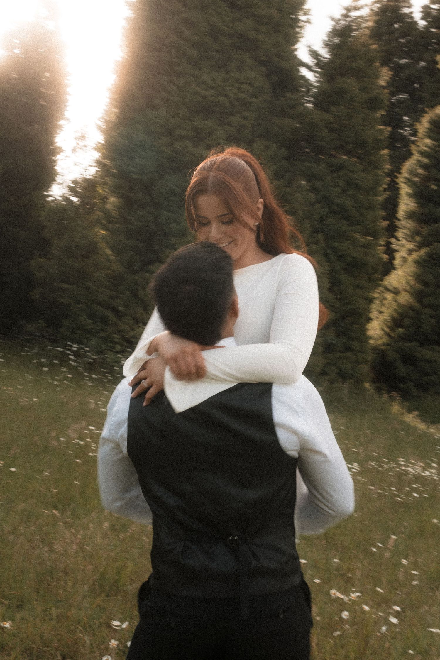A tender embrace captured between a couple in formal attire against a nature setting with evening light.