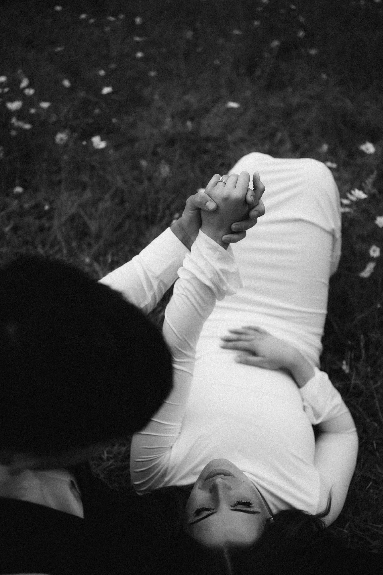 A sequence of black and white artistic photos showing a person lying down on grass in white clothing.