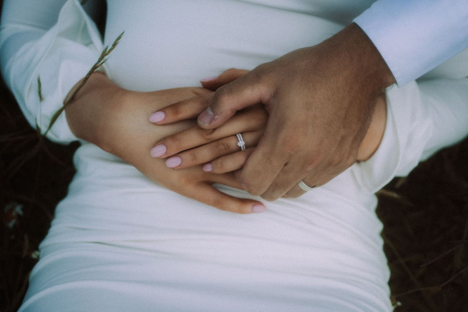 Close-up shots of hands gently resting against a white fabric in a minimalist style.