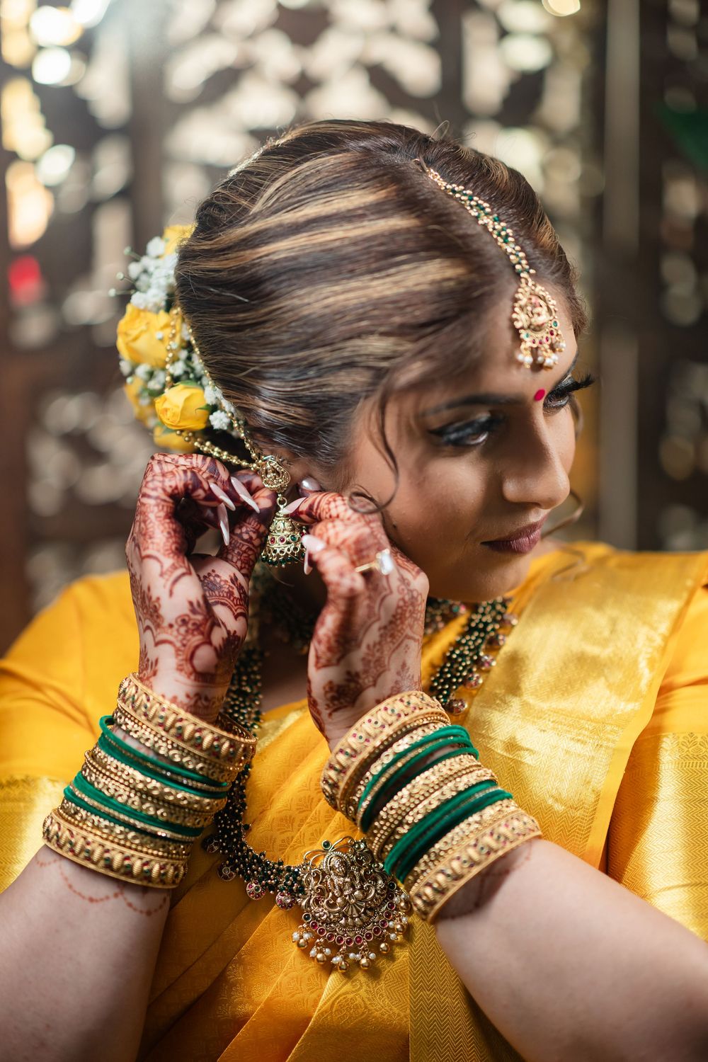 Close-up details of traditional Indian bridal jewelry and accessories against a vibrant yellow silk saree background.