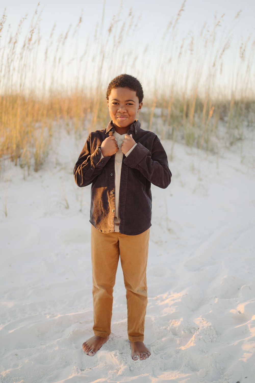 A series of photos showing a small child in khaki pants and dark jacket playing on a sandy beach with sea grass.