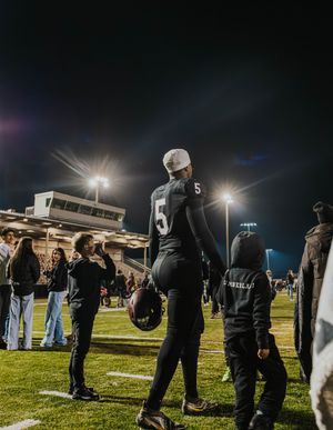 Crowd gathered on a football field at night with stadium lights illuminating the scene.
