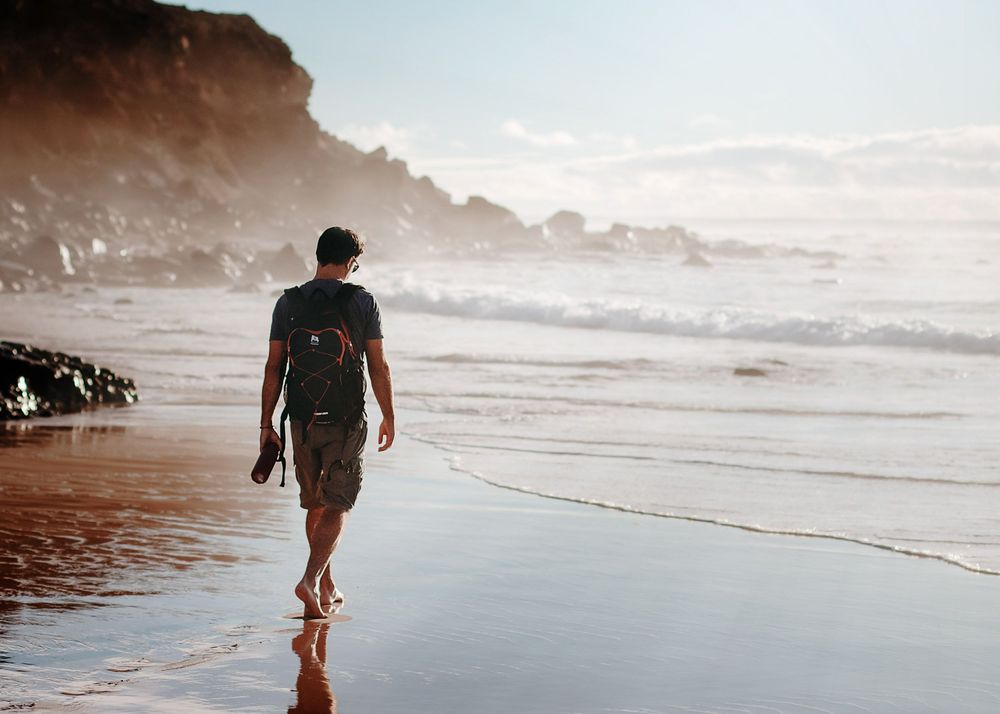 Andrius walking along the tide line with his camera gear - Fuerteventura adventure photographer at work