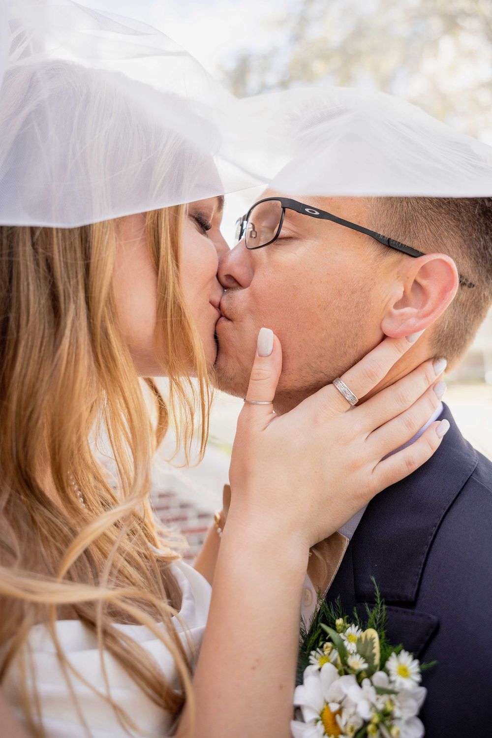 A romantic series of close-up wedding kisses between a couple, with white daisies in the bridal bouquet.