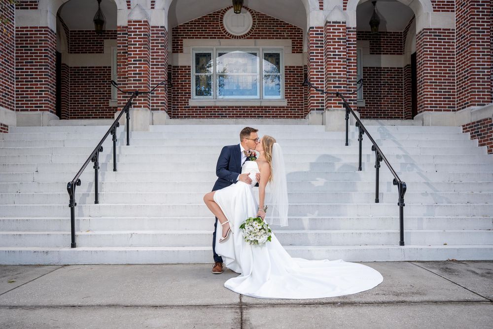 A romantic moment shared between a couple on the steps of a grand brick building with white columns.