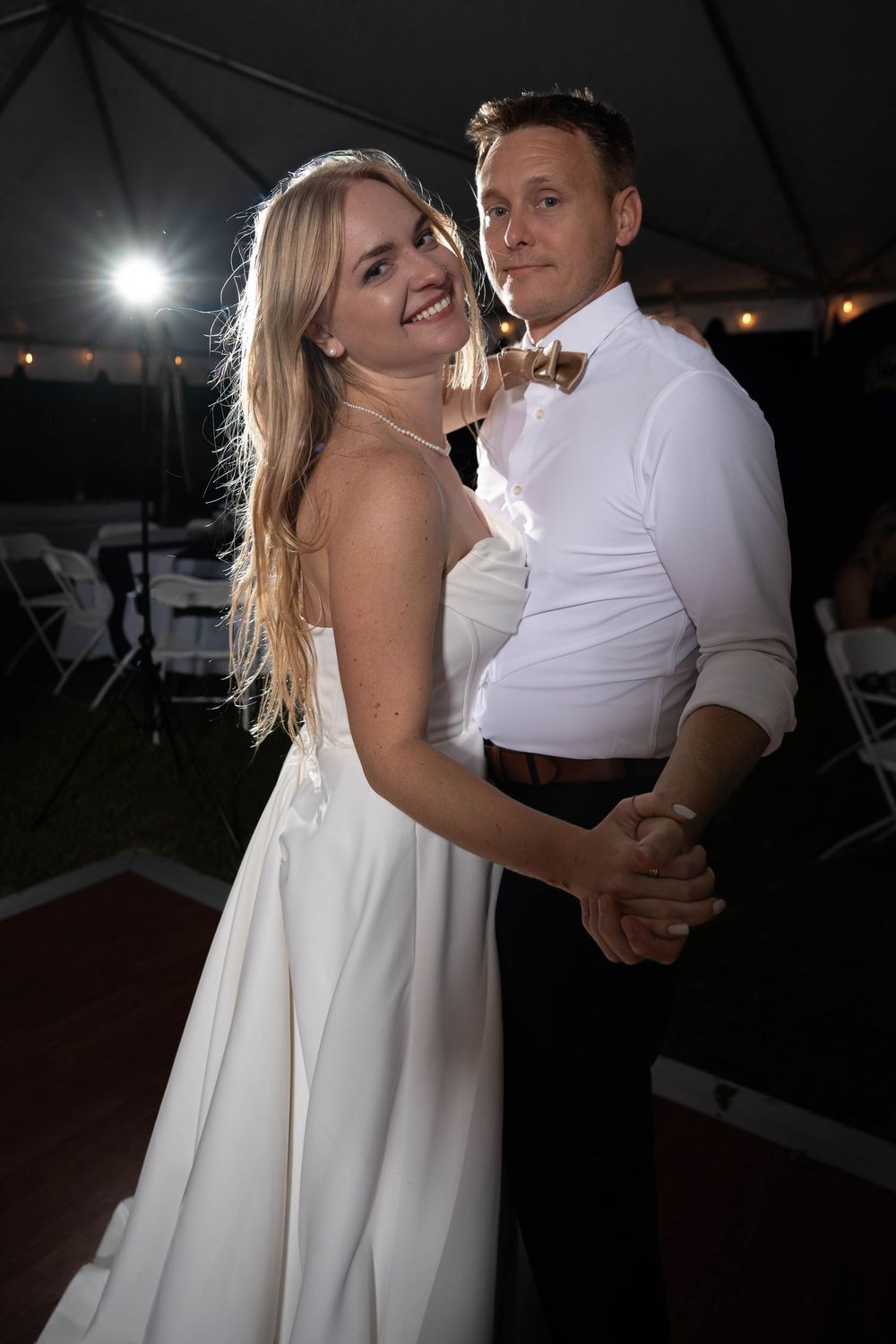 A couple shares a romantic dance moment at their wedding reception under evening lighting.