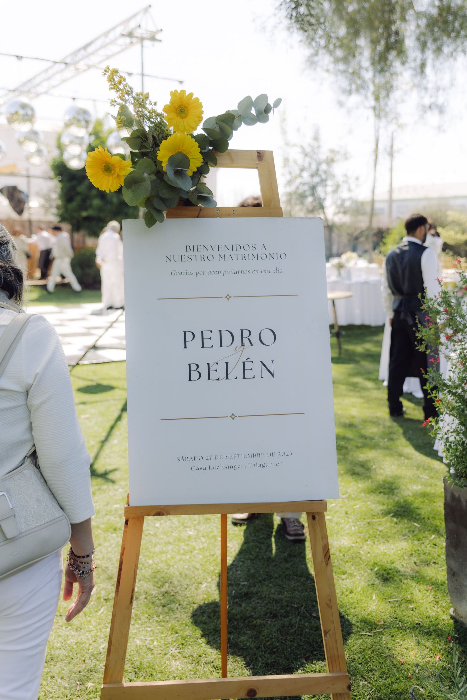 Wedding welcome sign for Pedro and Belen decorated with yellow sunflowers on easel.