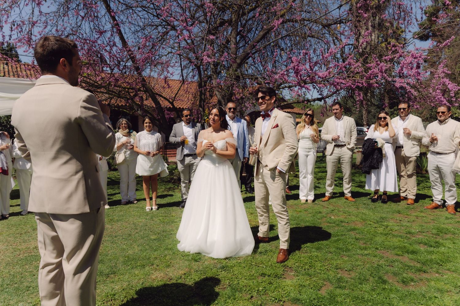 Bride and groom standing before guests during an outdoor spring wedding ceremony.