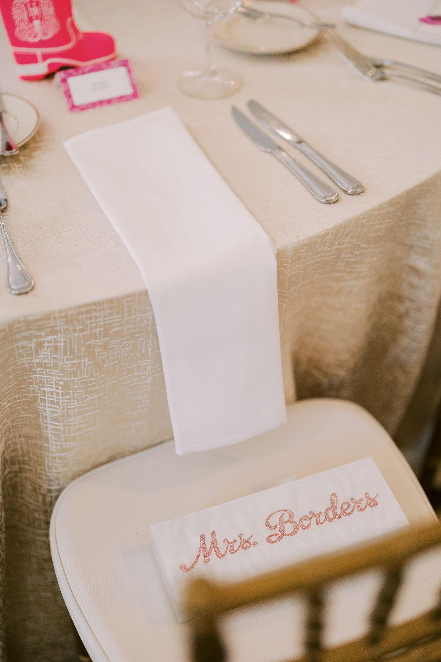 Close-up view of elegant wedding reception place settings with embroidered name cards on a beige tablecloth.