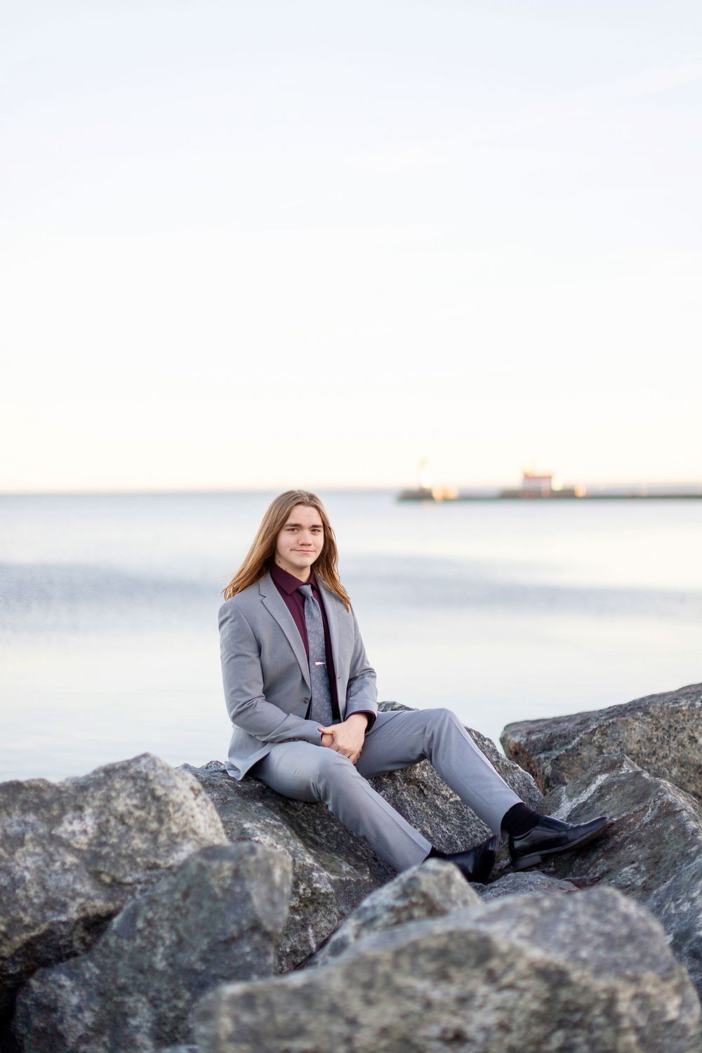 Professional photoshoot on coastal rocks at golden hour with calm waters in the background.