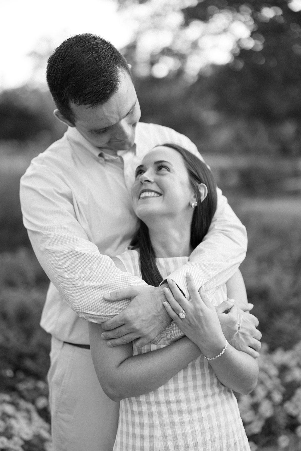 A romantic black and white photo series showing a couple in white clothing embracing tenderly in an outdoor setting.