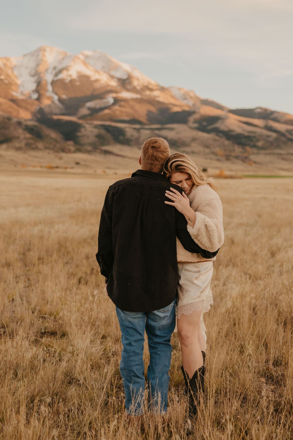 Western couple embraces under the mountains in Paradsie valley for their engagement photos captured by Montana Photographer in Pray, Montana