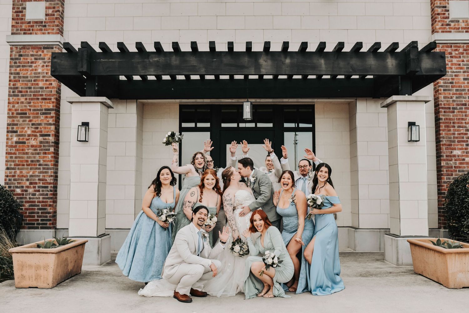 Bridal party posing outdoors in winter light with modern greenery and white florals