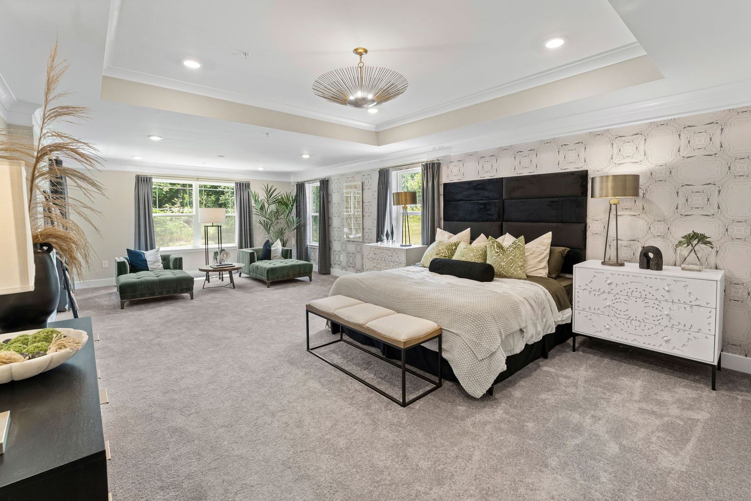 Elegant bedroom featuring tray ceiling, chandelier, and neutral color palette.