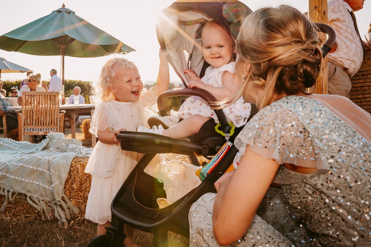 Wedding guests celebrate and dance during an outdoor reception under string lights at dusk.