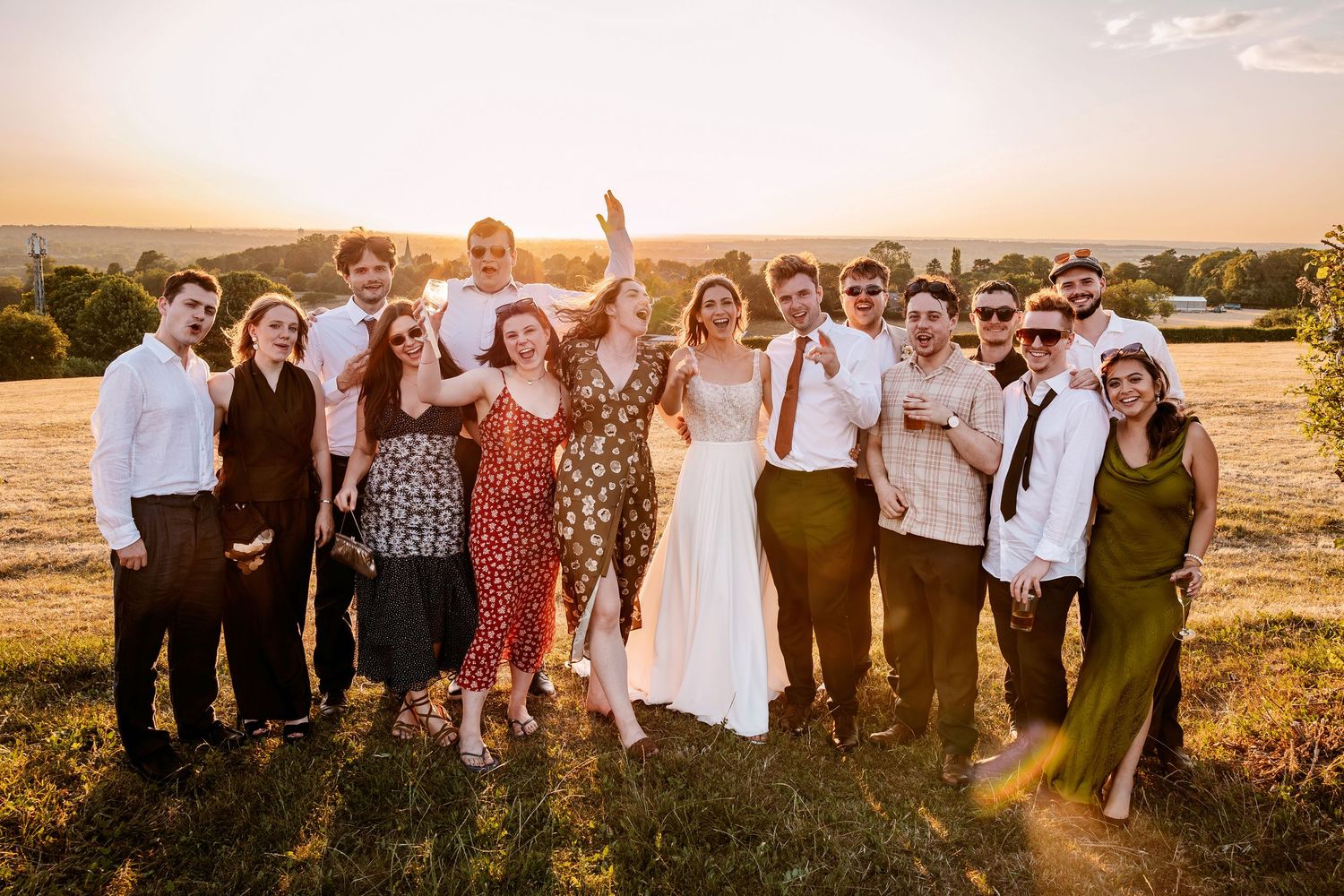 A series of outdoor sunset wedding photos showing groups of people gathered in a golden field during golden hour.