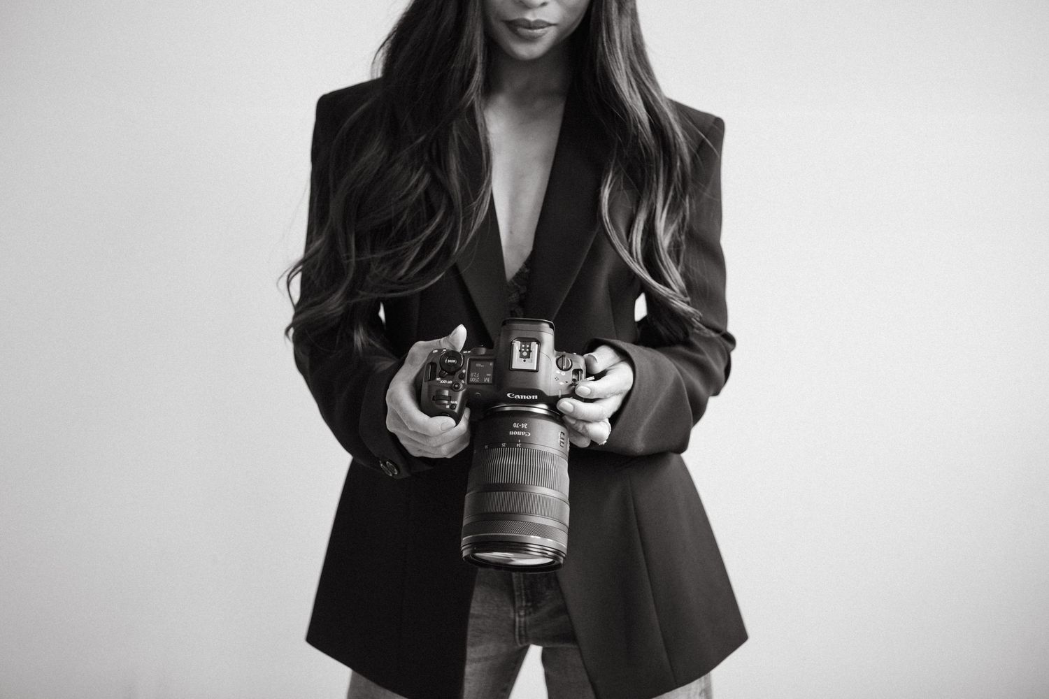 Person lying on brown couch using smartphone in bright room with natural light from windows.