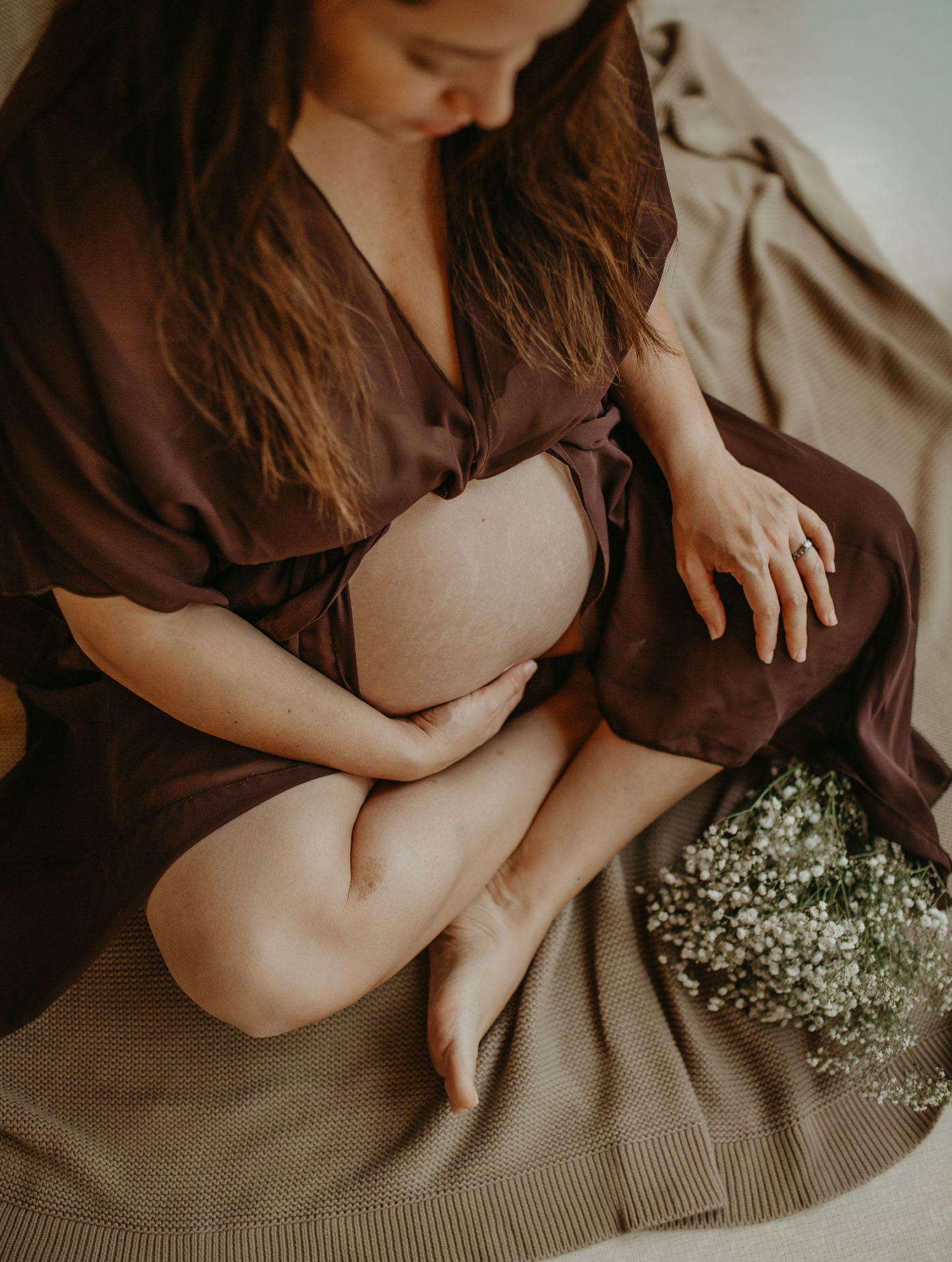A series of soft, moody photos showing hands resting on beige fabric with delicate baby's breath flowers creating an ethereal mood.