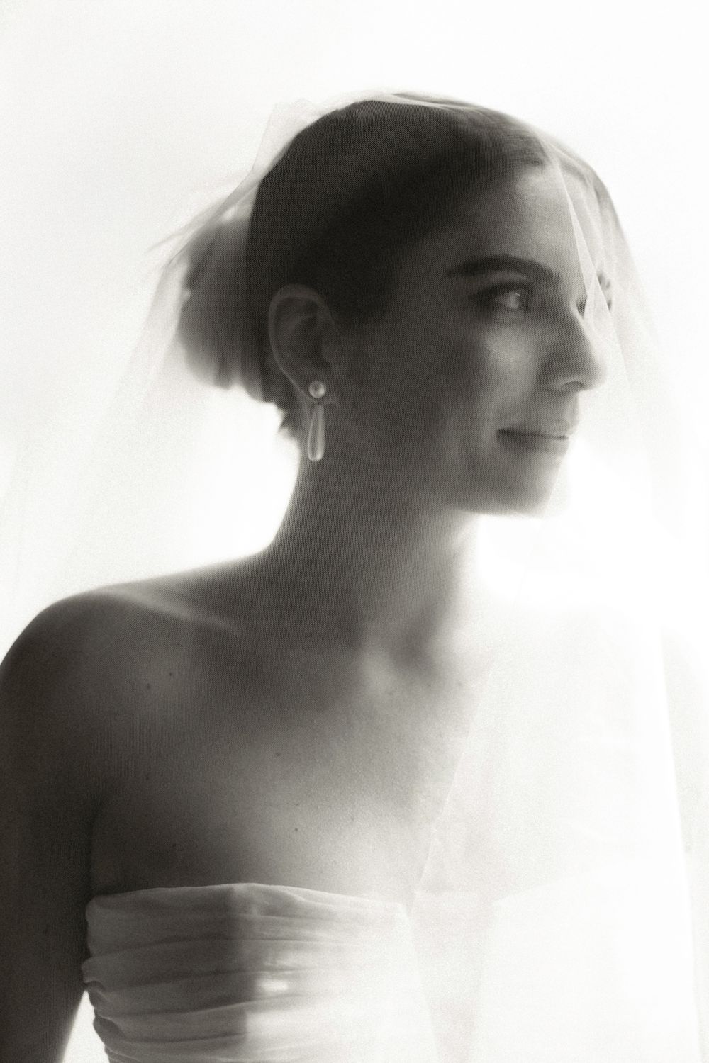 Black and white portrait of a person in profile wearing a strapless dress with soft lighting and dreamy effect.