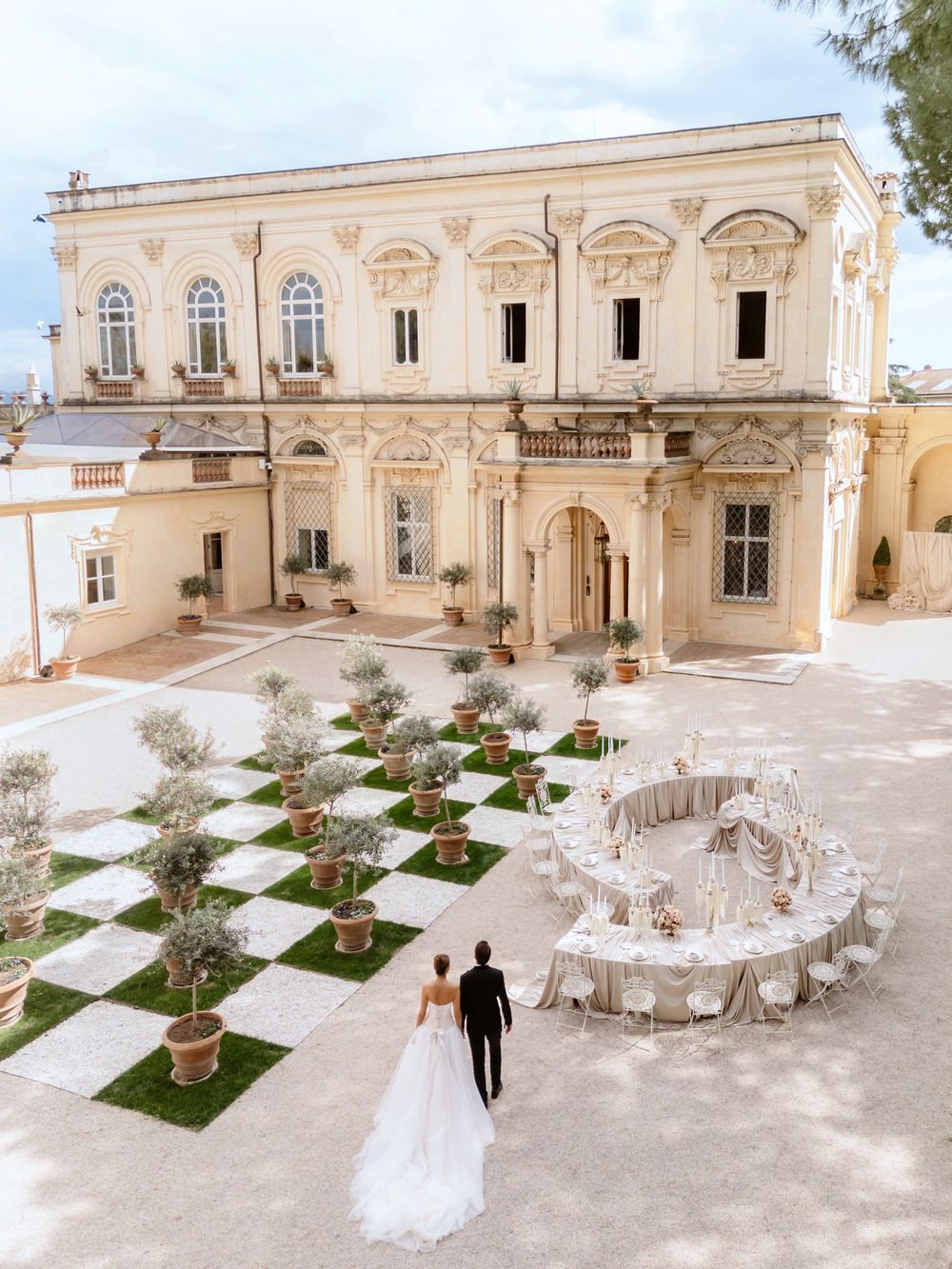 wedding venue with classic architecture features a checkerboard courtyard and circular table setup for outdoor reception villa Aurelia