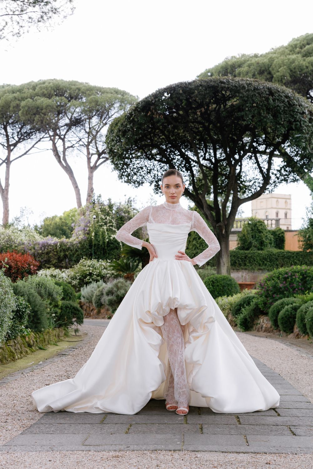 A bridal photoshoot in a garden setting featuring elegant white wedding gowns and stone pathways at Villa Aurelia