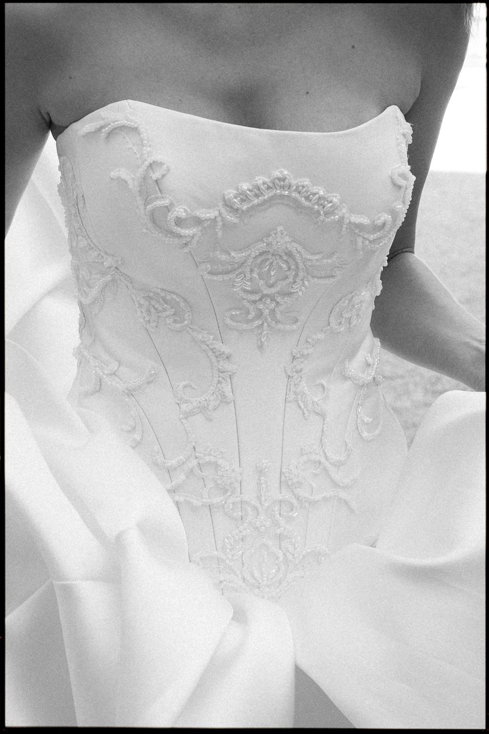 Close-up black and white photo of an elegant wedding dress bodice with intricate floral embroidery and beading details.