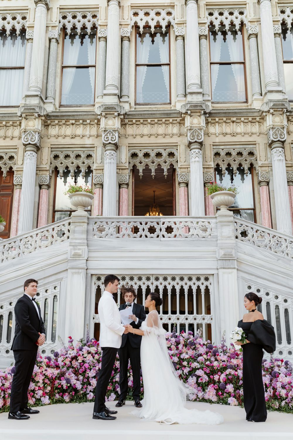 Elegant wedding ceremony setup at ornate white palace with pink floral decorations. Kempinski Palace Istanbul