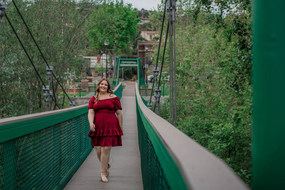 A scenic green pedestrian bridge surrounded by lush trees and foliage.