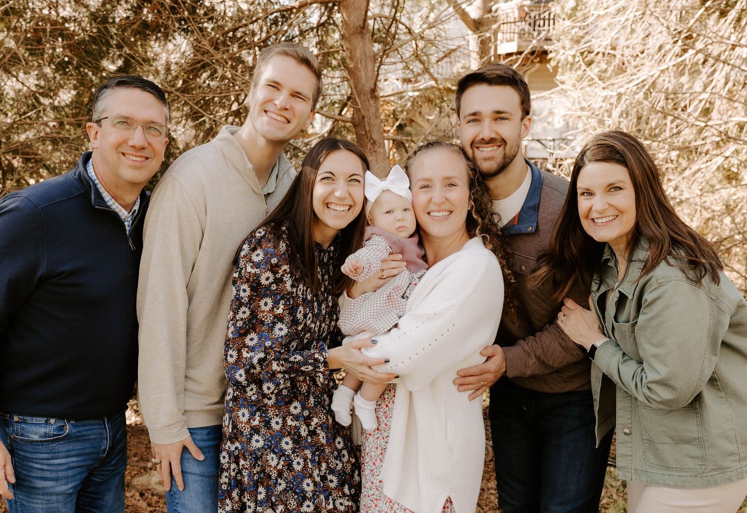 A group of people smiling together outdoors in casual clothing during a fall photoshoot.