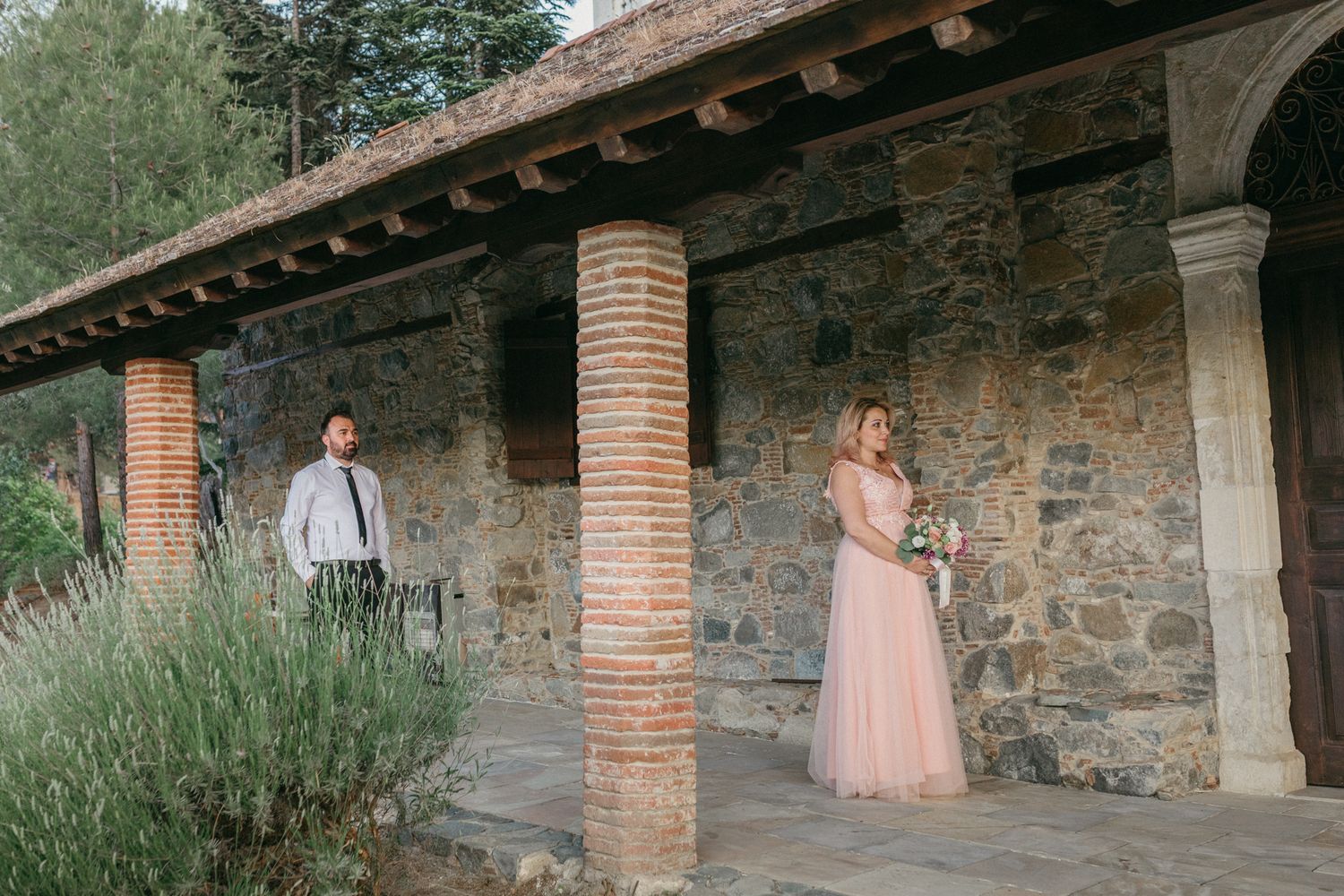 A rustic stone wall with brick columns creates a romantic backdrop for an outdoor photo session in soft natural lighting.