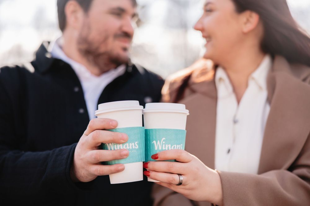 Couple sharing coffee cups and enjoying intimate conversation at an outdoor cafe.
