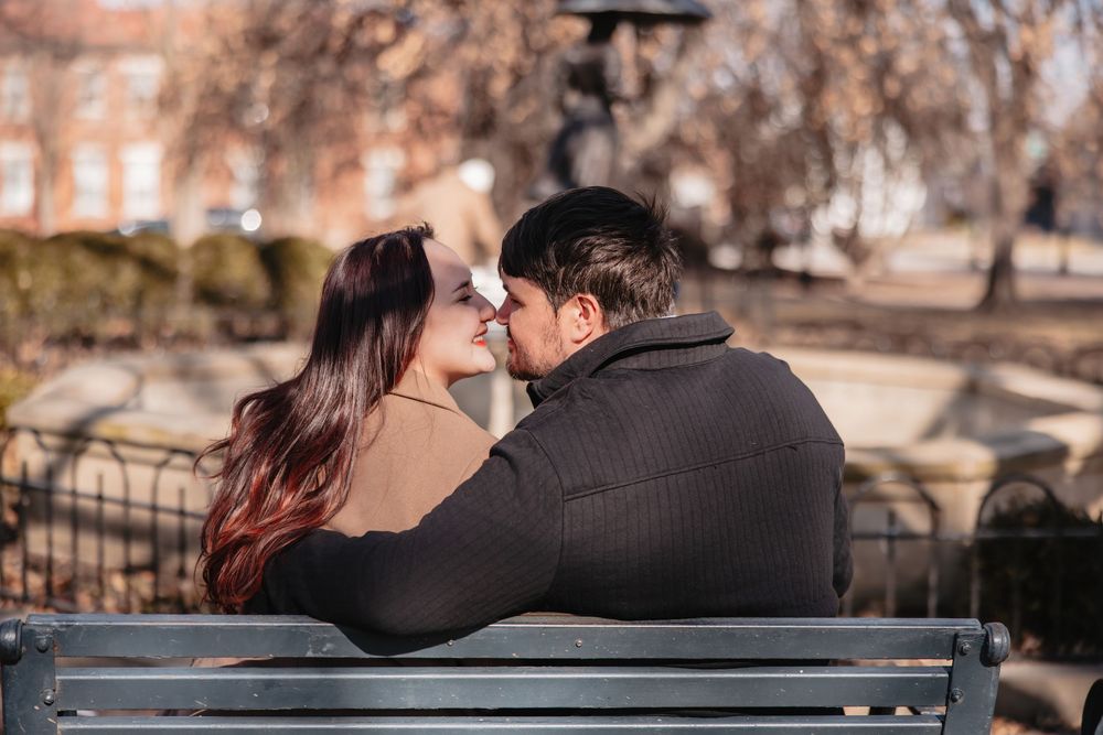 Romantic couple sitting close together on a park bench during autumn.