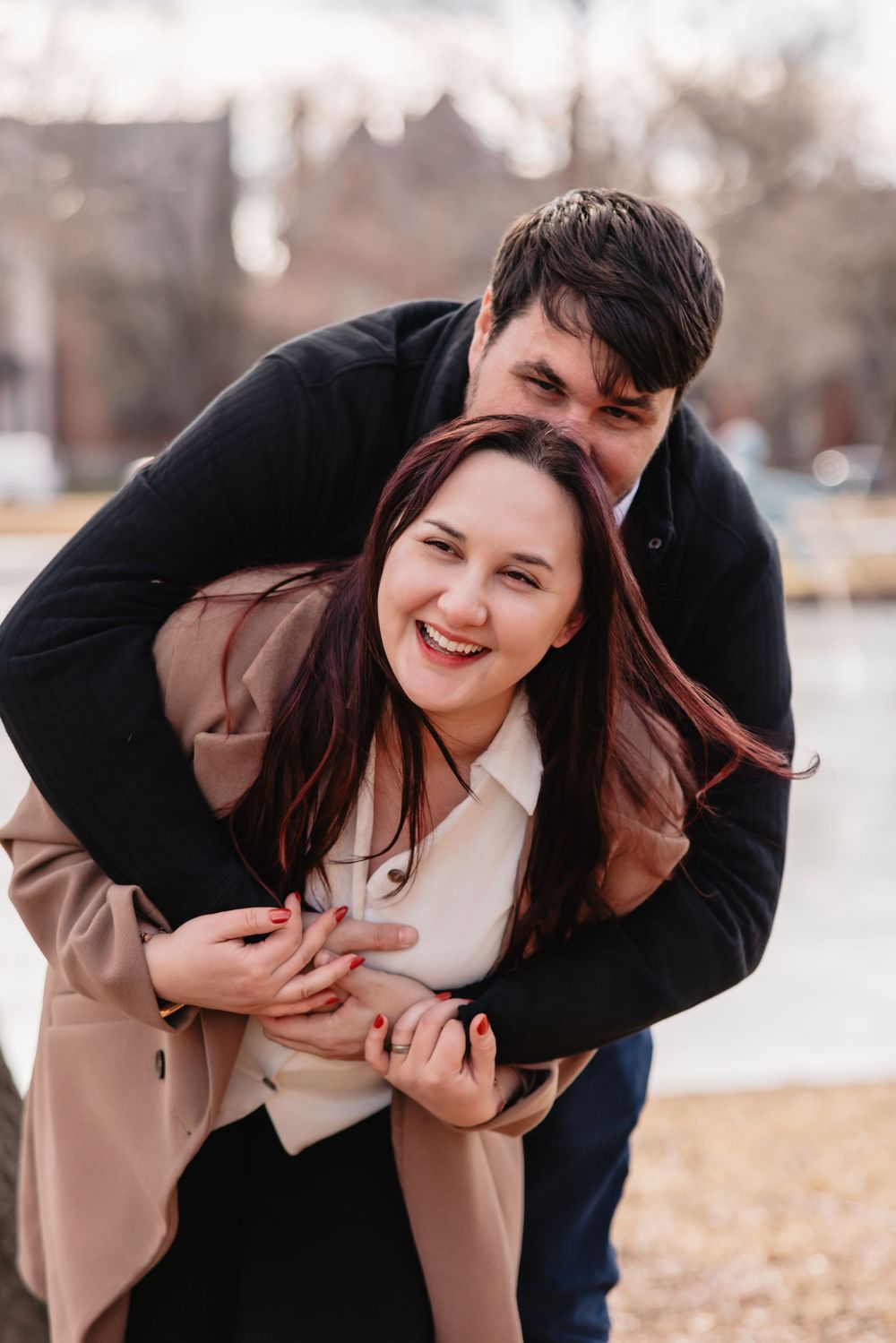 A playful couple shares a joyful moment together outdoors during an autumn photoshoot.