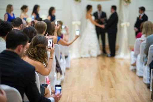 Wedding guests use smartphones to capture special moments during a reception celebration.
