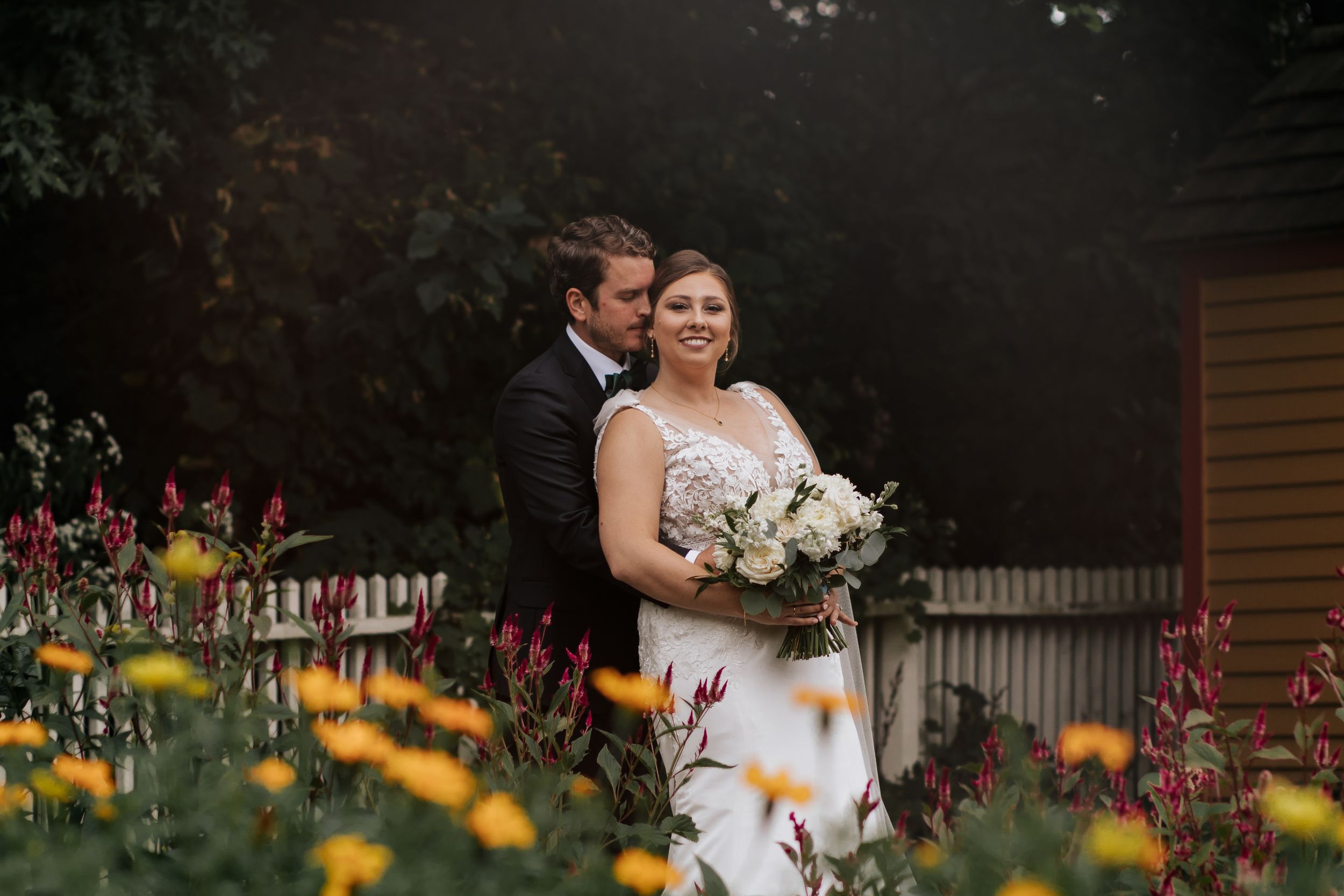 Romantic garden wedding moment with yellow flowers in foreground.
