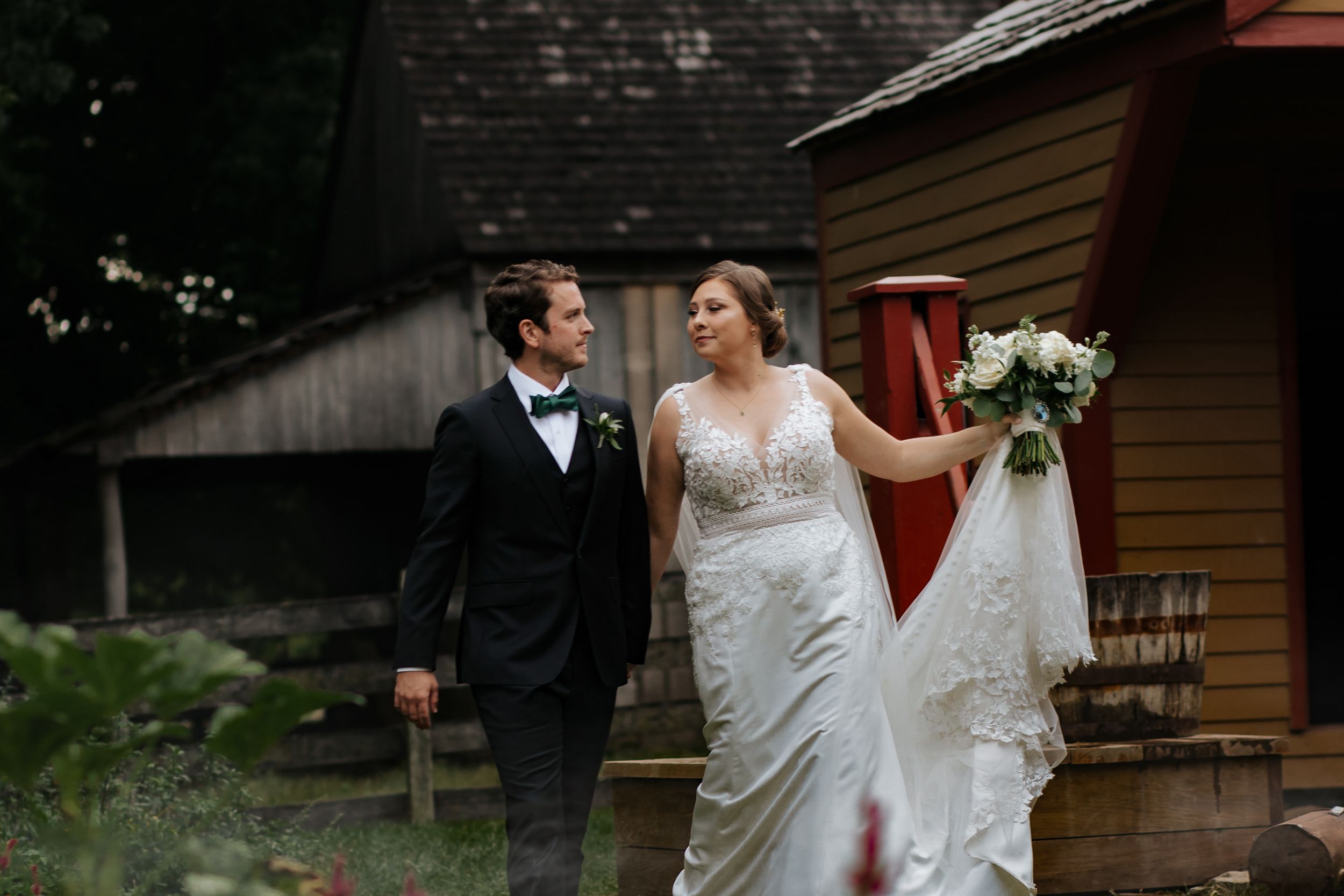 Couple sharing intimate moment during outdoor wedding near rustic cabin.